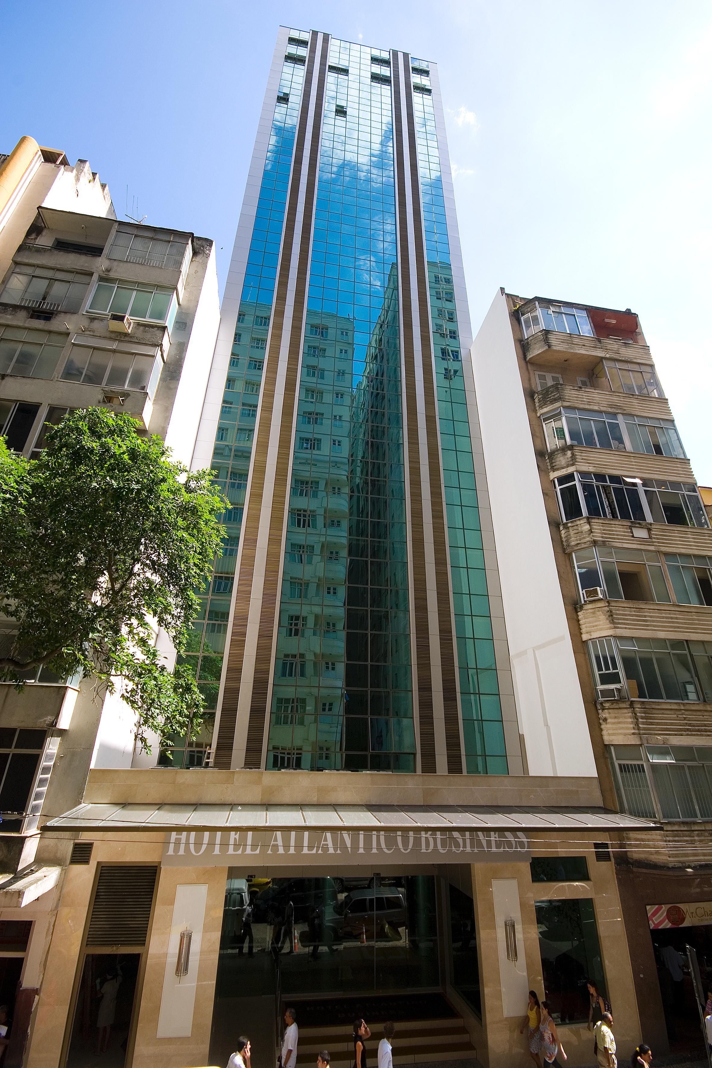 ריו דה ז'ניירו Hotel Atlantico Business Centro מראה חיצוני תמונה The photo shows a modern multi-story building with a sleek glass facade. The building appears to have several floors with large windows, reflecting sunlight, and is flanked by a tree on one side and an older, more traditional residential structure on